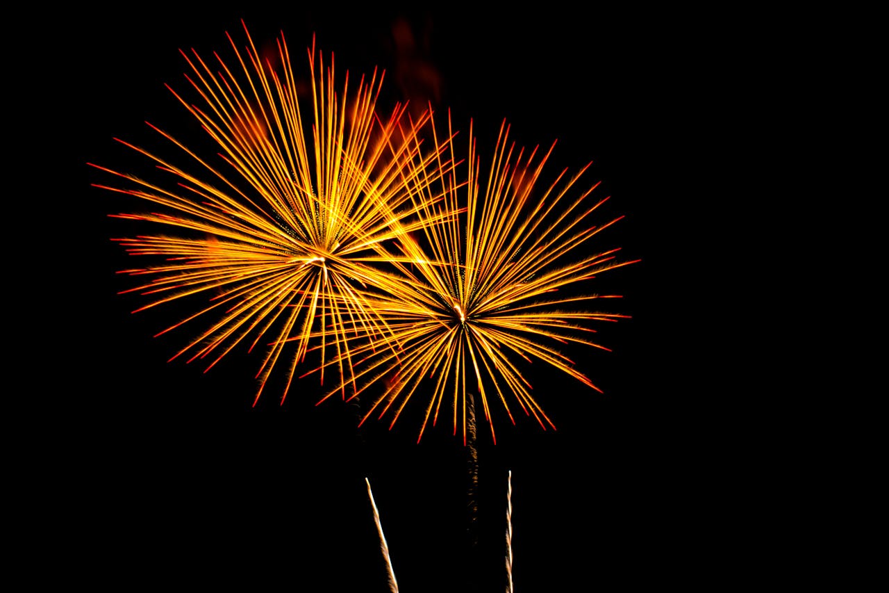 Bright yellow fireworks burst over a night sky, celebrating a festive occasion.