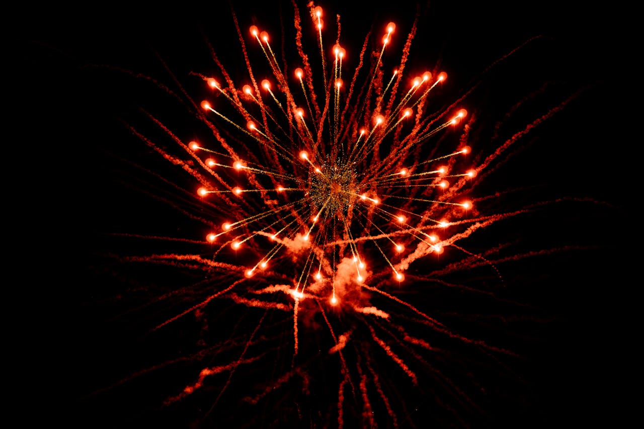 Dramatic red fireworks exploding against a dark night sky, capturing a festive celebration.